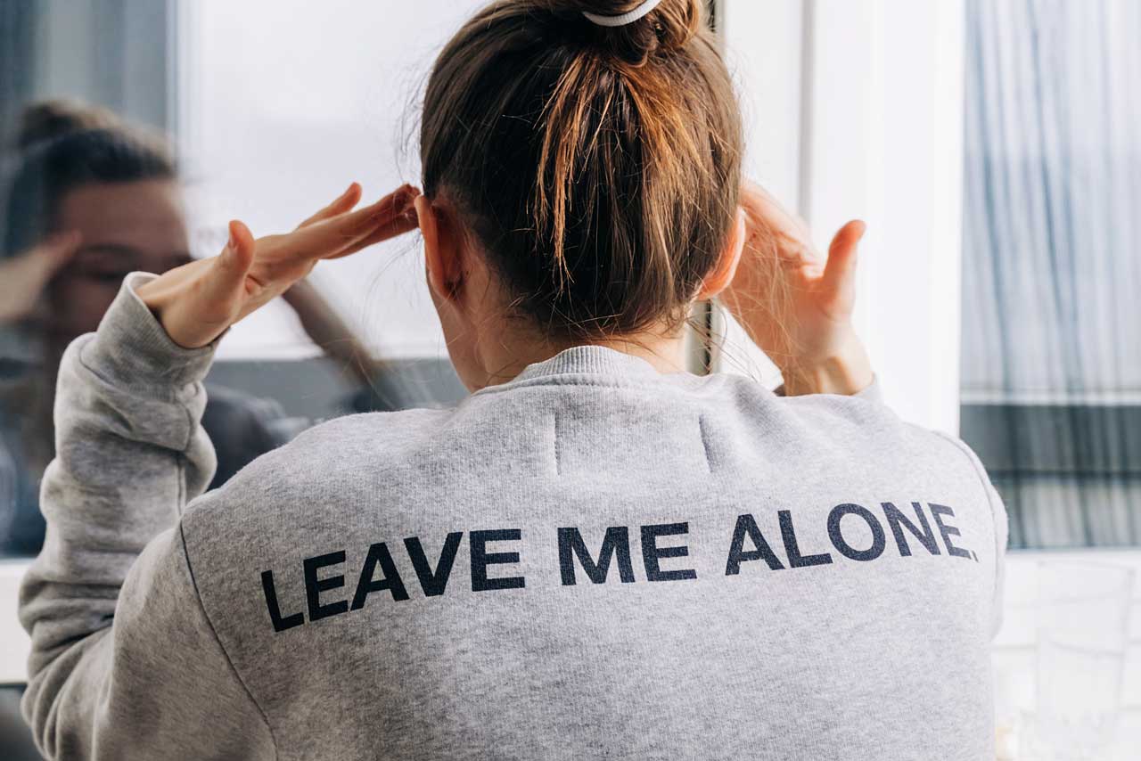Una mujer ante el espejo con una camiseta que pone "déjame sola"